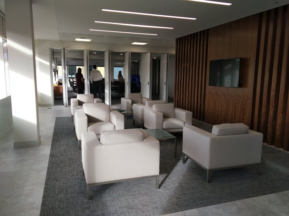 Photo shows a breakout area in the Bristol office, white sofas and chairs, and a TV alongside. 